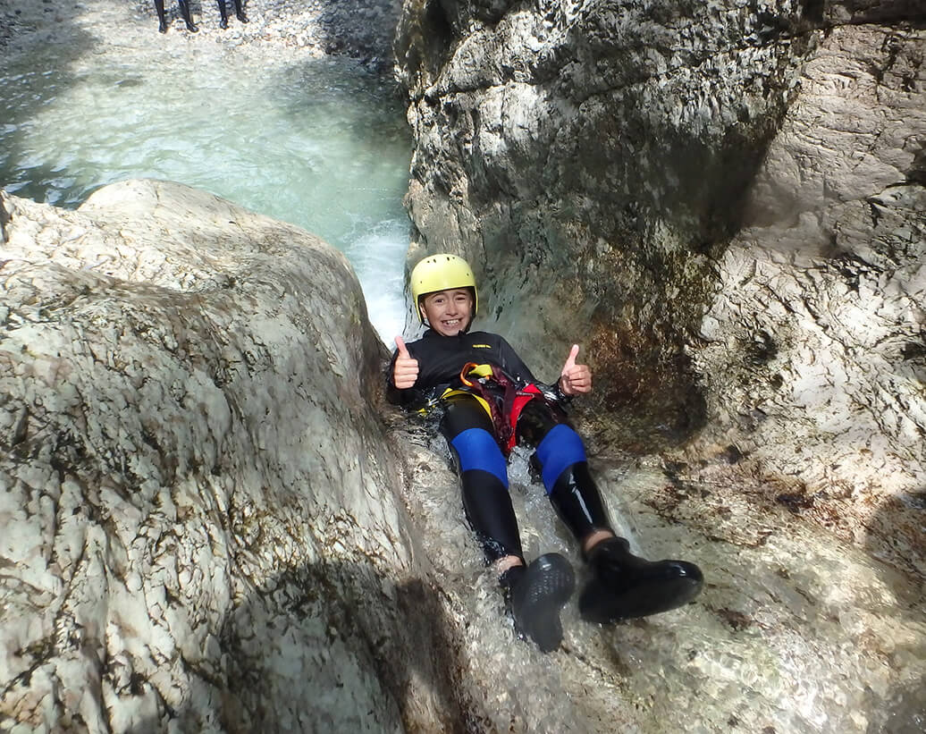 Canyoning Bovec Slovenia Sušec canyon | A kid is sliding in waterfall of Sušec canyon, Bovec, Slovenia